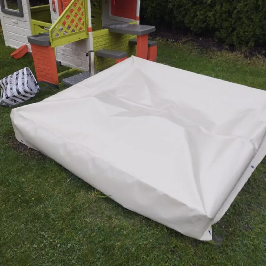 Weiße Abdeckung schützt Spielplatz im Garten vor Witterung.